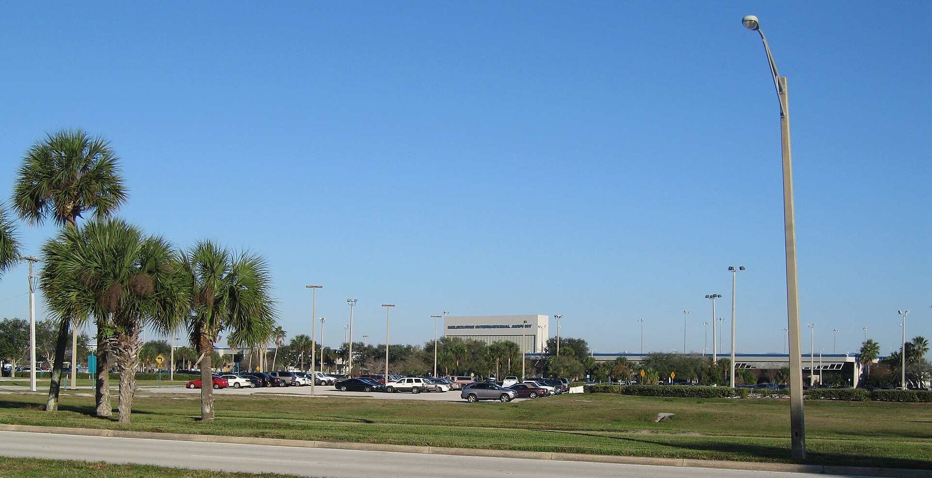 The entrance and front terminal of Orlando Melbourne International Airport in Melbourne, Florida, with palm trees in the foreground.
