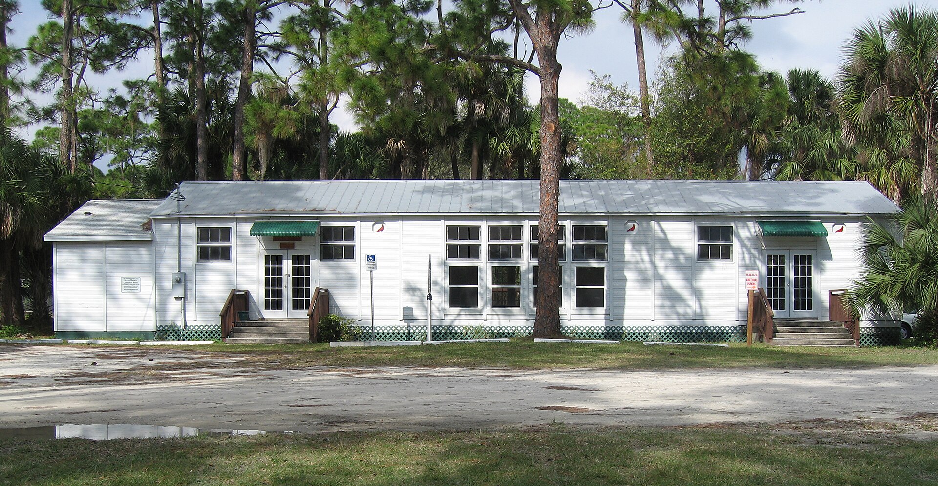 The original Melbourne Village Hall, a small wooden building with a porch and historical marker, used by the planned community since 1946.